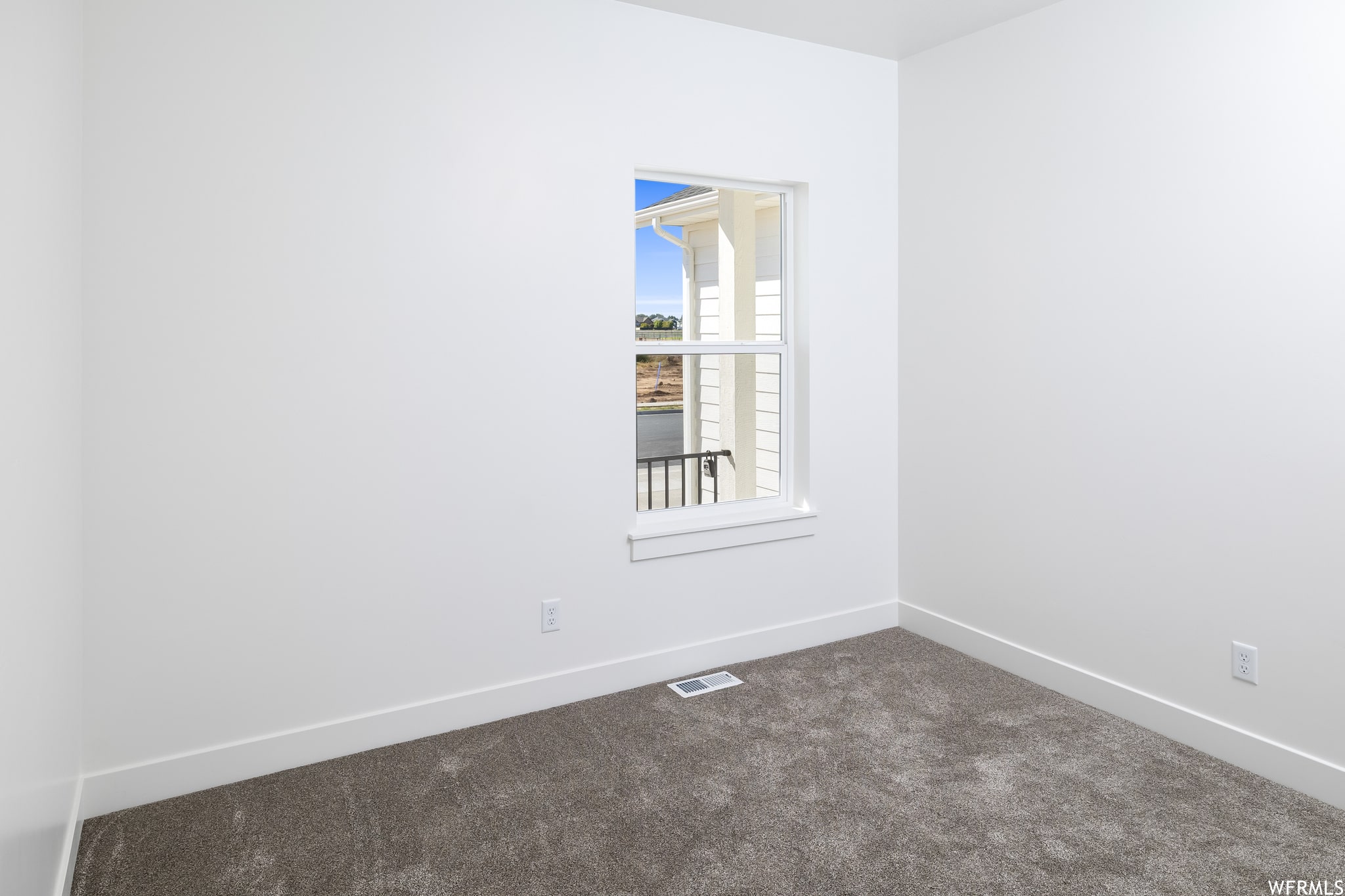 Unfurnished room featuring baseboards and dark carpet