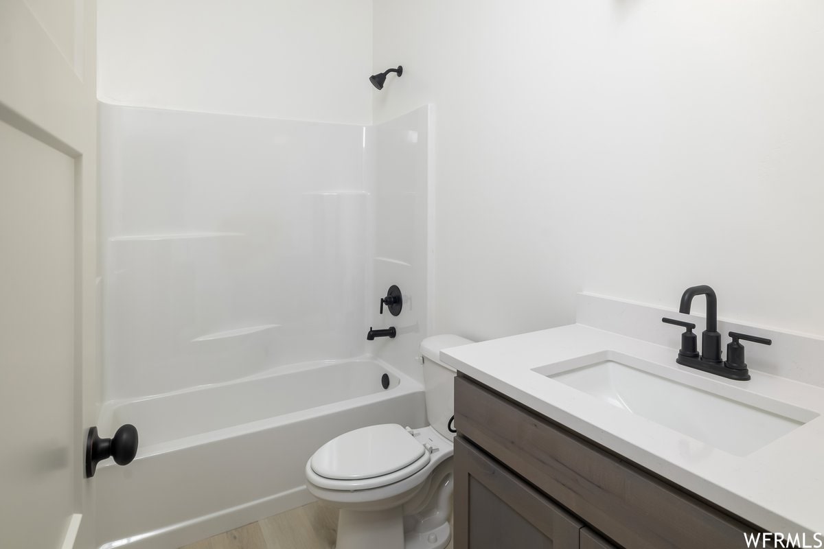 Full bath with vanity, shower / tub combination, and light wood-style flooring