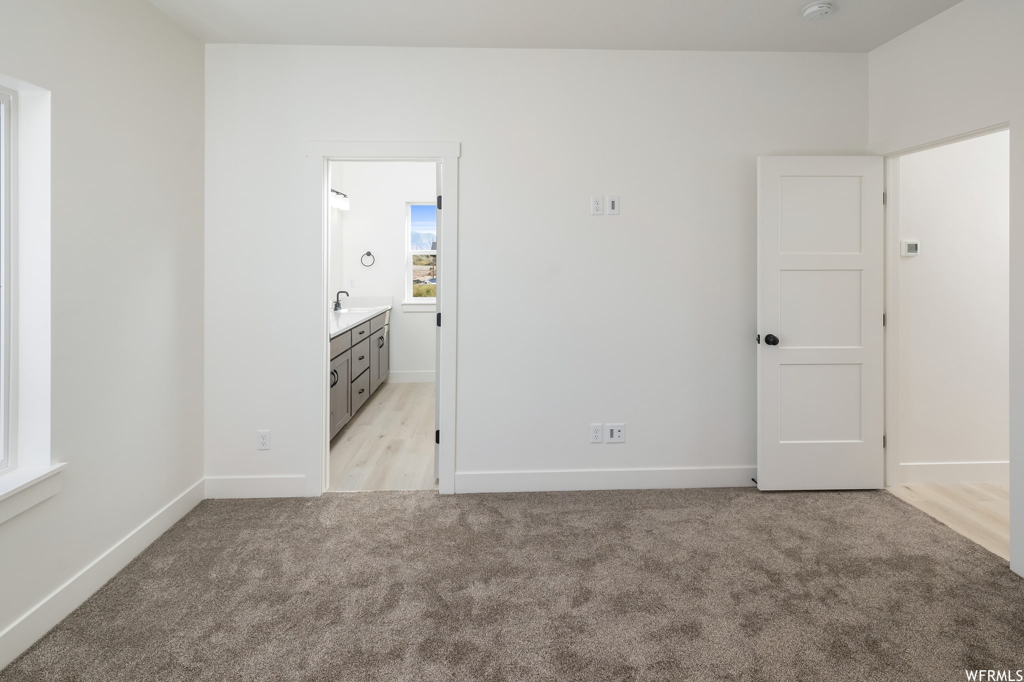 Unfurnished bedroom with light carpet and ensuite bathroom