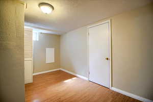 Spare room featuring a textured wall, a textured ceiling, and light wood-style floors