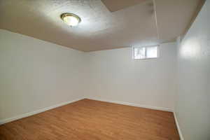 Below grade area with a textured ceiling and light wood-type flooring