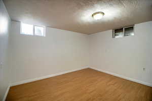 Below grade area with a textured ceiling and wood finished floors