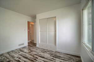 Unfurnished bedroom featuring a closet, wood finished floors, and multiple windows