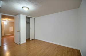 Unfurnished bedroom with a textured ceiling, light wood finished floors, and a closet