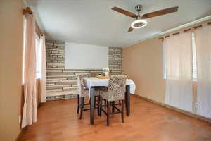 Dining area featuring ornamental molding, light wood-style flooring, and a ceiling fan