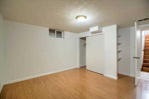 Unfurnished bedroom with a textured ceiling, a closet, and light wood-style flooring