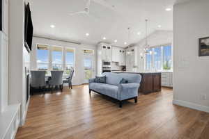 Living area with ceiling fan, light wood-style floors, hanging lights, and a high ceiling