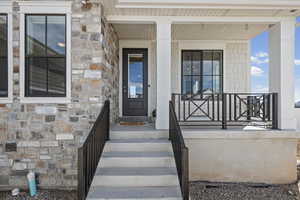 Property entrance featuring stone siding and a porch