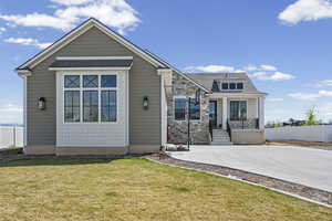 View of front facade featuring stone siding, a shingled roof, and a porch