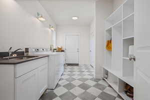 Laundry area featuring light floors, independent washer and dryer, and cabinet space