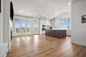 Spacious open-concept living area featuring wood-finish flooring, vaulted ceilings, and recessed lighting