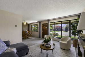 Living room with carpet, a ceiling fan, and front door