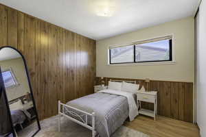 Bedroom featuring wooden walls, light wood-type flooring, and a closet