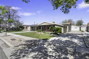 Ranch-style home featuring a garage, an outbuilding, brick siding, and a chimney