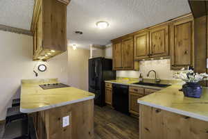Kitchen featuring a peninsula, a kitchen bar,  light countertops, and wood finish cabinetry