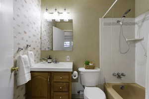 Full bath featuring vanity, wallpapered walls, and tub / shower combination