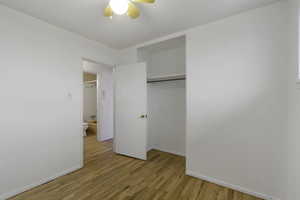 Unfurnished bedroom featuring light wood finished floors, a closet, and a ceiling fan