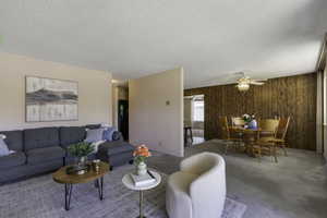 Living area featuring wood panel walls, a dining table, and ceiling fan
