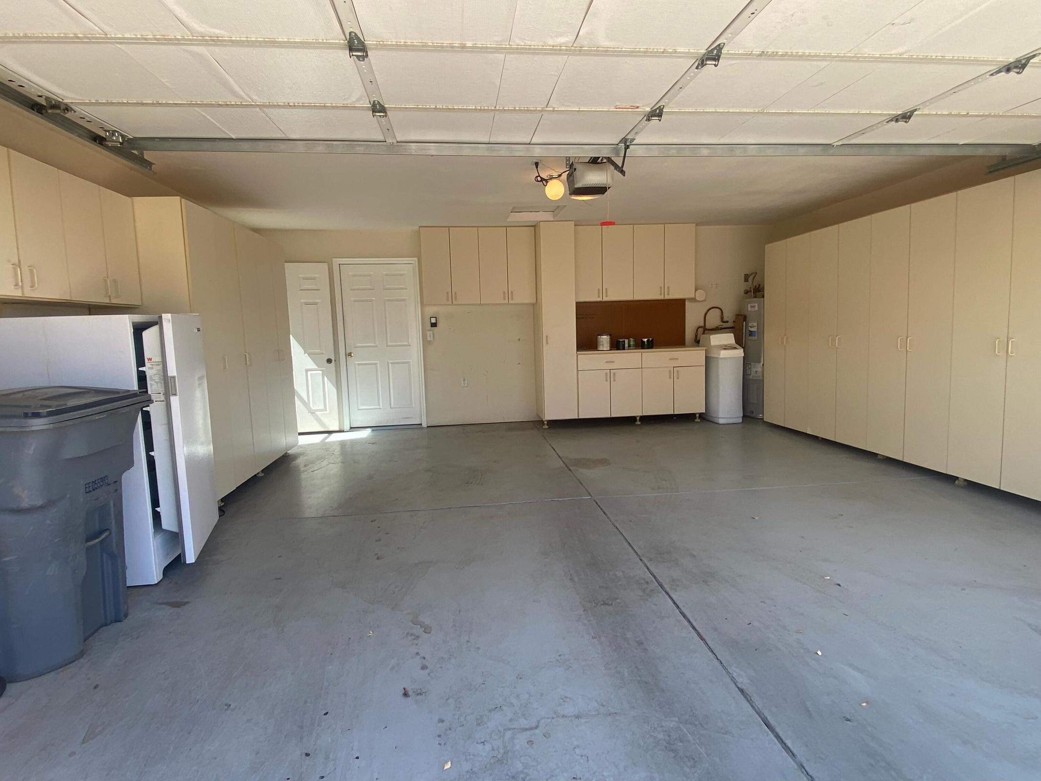 Spacious garage featuring extensive built-in cabinetry, a utility sink, and durable concrete flooring