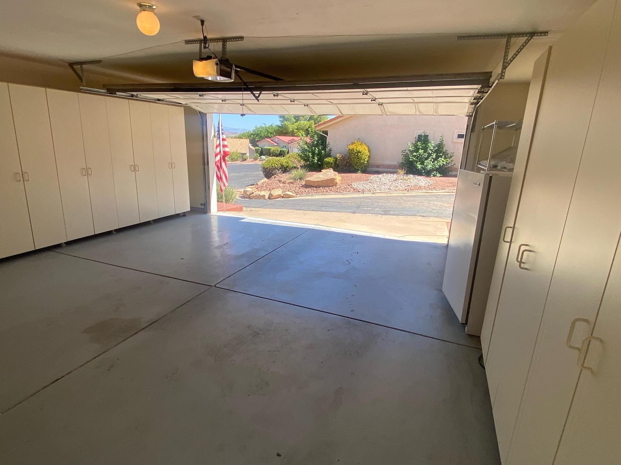 Spacious garage featuring extensive built-in storage cabinetry, a finished concrete floor, and an overhead garage door opener