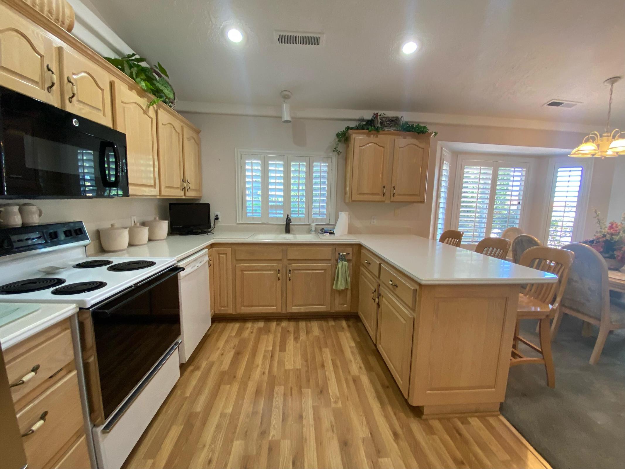U-shaped kitchen featuring light wood cabinetry and wood-finish flooring