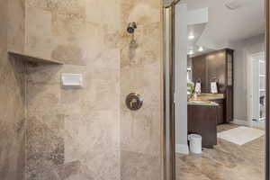 Full bath with vanity, tiled shower, and recessed lighting