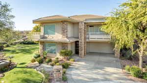 View of front of property with a balcony, stucco siding, a garage, a front lawn, and driveway
