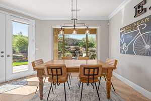 Dining area featuring ornamental molding, wood finished floors, and a chandelier