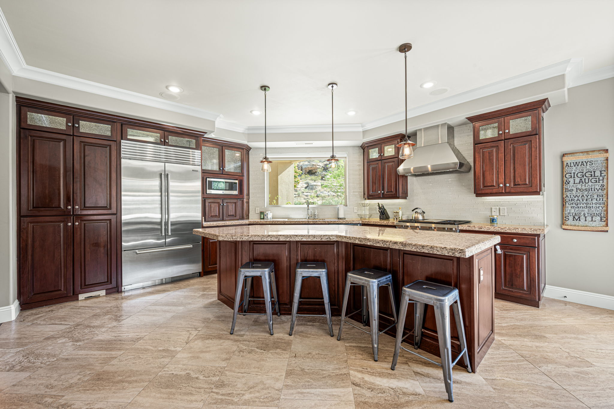 Kitchen with glass fronted cabinets, built in appliances, crown molding, a kitchen breakfast bar, and a kitchen island with sink