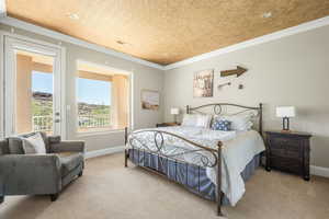Carpeted bedroom with access to exterior and ornamental molding