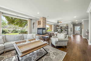 Living area with ornamental molding, dark wood-style floors, recessed lighting, a fireplace, and ceiling fan