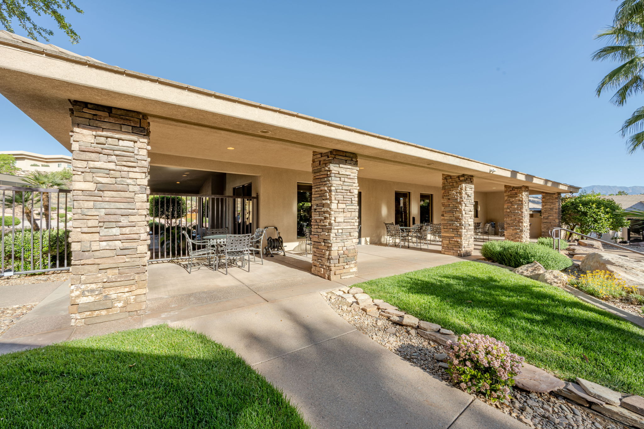 Rear view of house featuring stucco siding, outdoor dining space, a patio, and stone siding