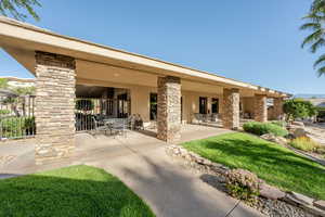 Rear view of house featuring stucco siding, outdoor dining space, a patio, and stone siding