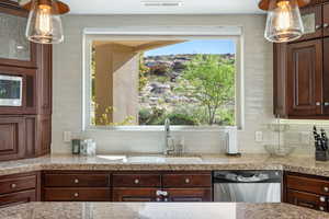 Kitchen with hanging light fixtures, stainless steel appliances, dark wood finish cabinetry, and glass insert cabinets