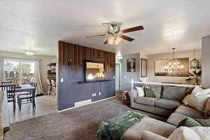 Carpeted living area featuring hanging lights, a ceiling fan, and a textured ceiling