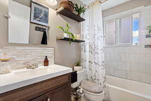 Full bath featuring shower / bathtub combination with curtain, backsplash, and vanity