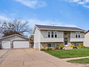 Split foyer home with a detached garage, an outdoor structure, a front yard, and brick siding