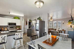 Dining room featuring light wood-style flooring, a textured ceiling, and a ceiling fan