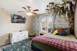 Carpeted bedroom featuring ceiling fan and an accent wall