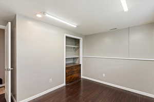 Spare room featuring dark wood-style flooring, a textured ceiling, and built in features