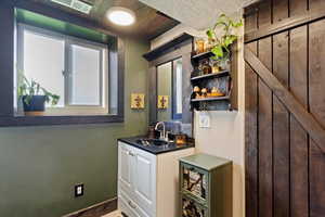 Bar area featuring open shelves, white cabinets, and dark countertops