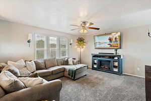 Living room with carpet flooring, ceiling fan, and a textured ceiling
