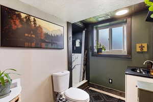 Full bathroom featuring vanity, a stall shower, and a textured ceiling