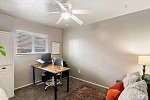 Office space with dark carpet and a ceiling fan