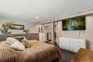 Bedroom with dark wood finished floors, a textured ceiling, and recessed lighting