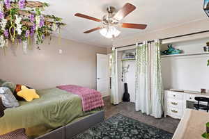 Bedroom with dark colored carpet, ceiling fan, and an office area