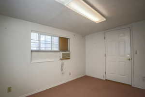 Carpeted spare room with a textured ceiling and cooling unit