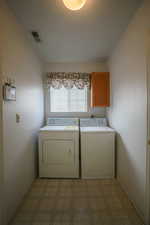 Laundry area featuring light flooring, cabinet space, and separate washer and dryer