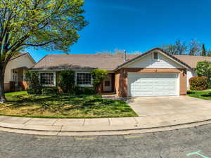 Ranch-style house featuring brick siding, a garage, driveway, and a tile roof