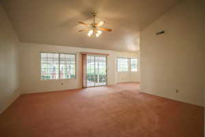Spare room featuring lofted ceiling, carpet, and a ceiling fan